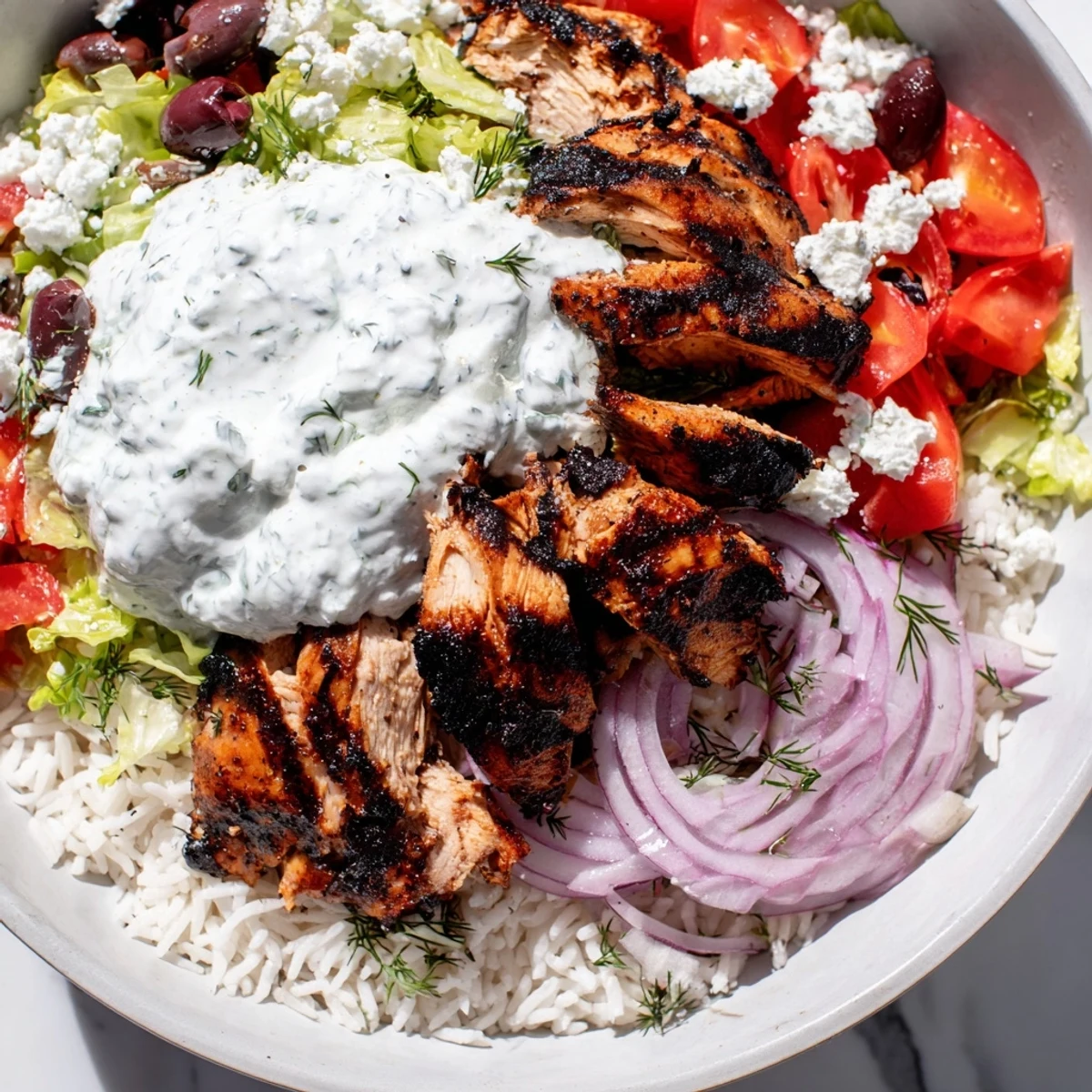Colorful Greek Chicken Gyro Bowls feature juicy chicken, fresh tomato slices, olives, feta, and a creamy dollop of tzatziki.