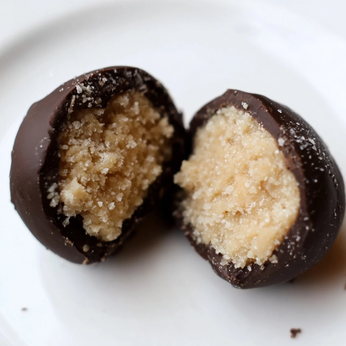 Freshly dipped Chocolate Peanut Butter Balls are arranged on a baking sheet, glistening with rich chocolate, a perfect no-bake dessert for parties or gifts.