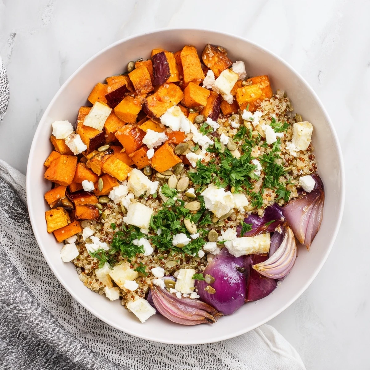 A vibrant bowl of Warm Quinoa Salad with Roasted Root Vegetables, featuring caramelized carrots and sweet potatoes glistening with lemon-herb dressing.