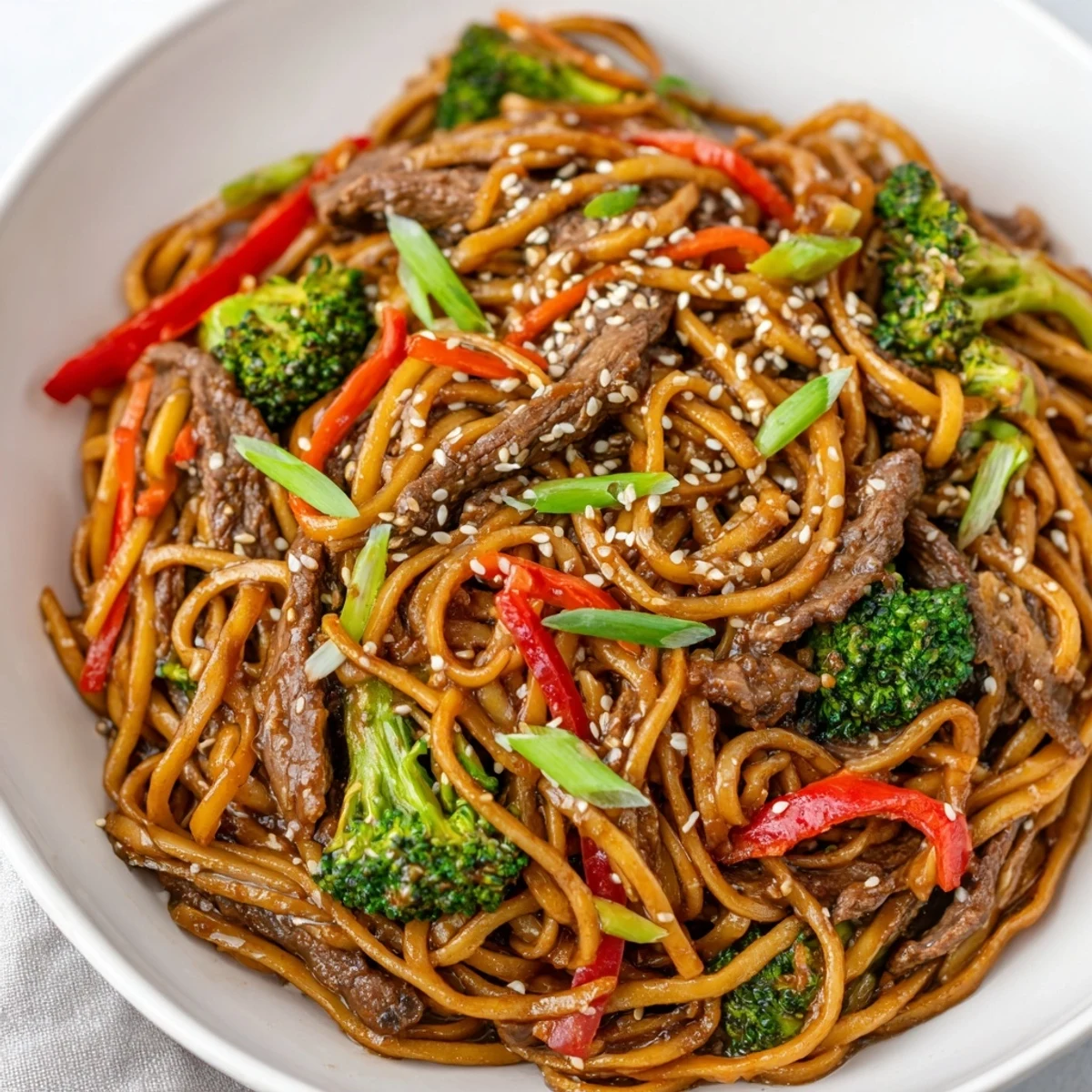 A close-up of a colorful serving of Beef and Broccoli Lo Mein reveals glistening noodles, juicy beef, and bright broccoli, perfect for an easy Asian-inspired dinner.
