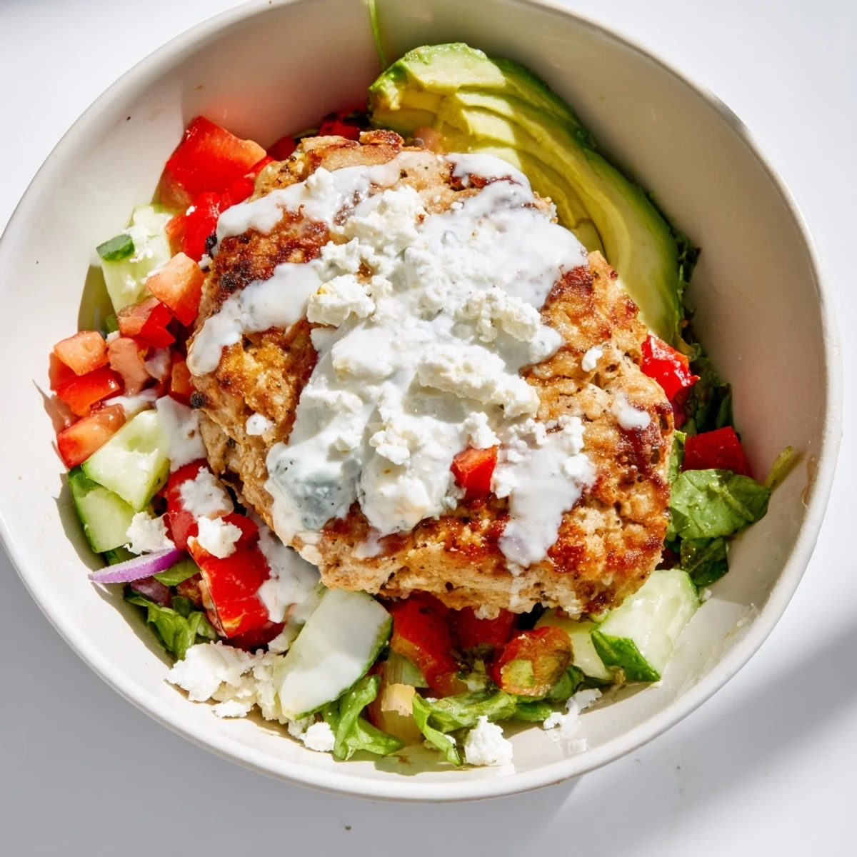 A vibrant Turkey Burger Salad Bowl with sliced turkey patties, crisp greens, and avocado on a white plate.