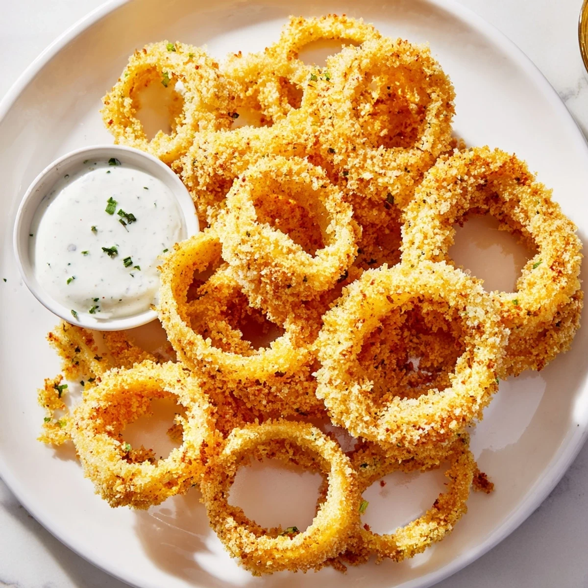 Homemade Touchdown Crispy Onion Rings with Ranch piled high, crunchy texture visible next to a bowl of dressing.