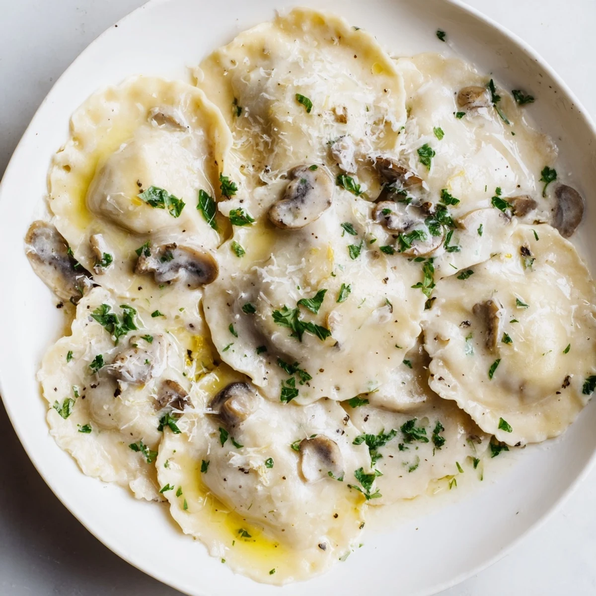 Silky truffle oil glistens on tender Date Night Mushroom Ravioli, paired with a glass of crisp white wine.