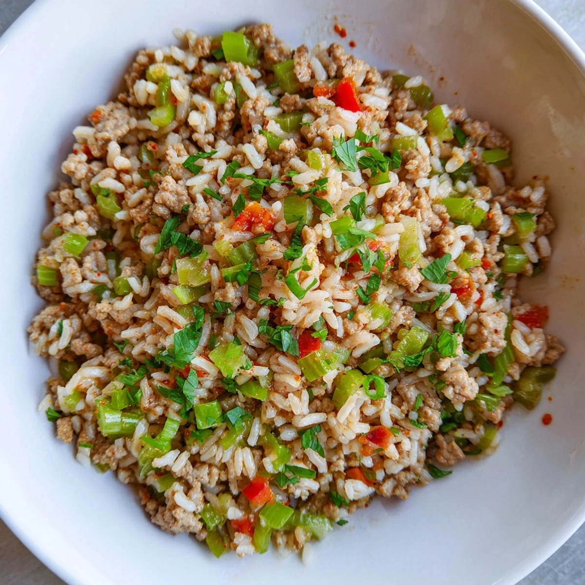 A close-up of Cajun Dirty Rice with Ground Turkey highlights tender turkey, sautéed bell peppers, and fluffy long-grain rice in a rustic bowl.