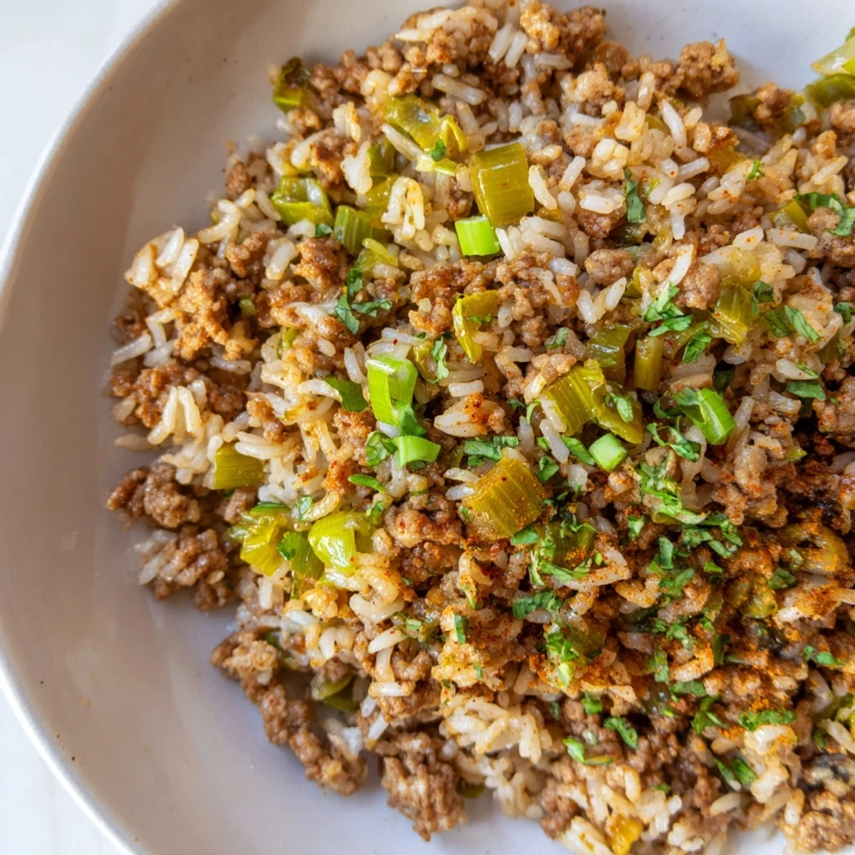 Cajun Dirty Rice with Ground Turkey steams in a skillet, garnished with fresh parsley and green onions, perfect with a side salad.