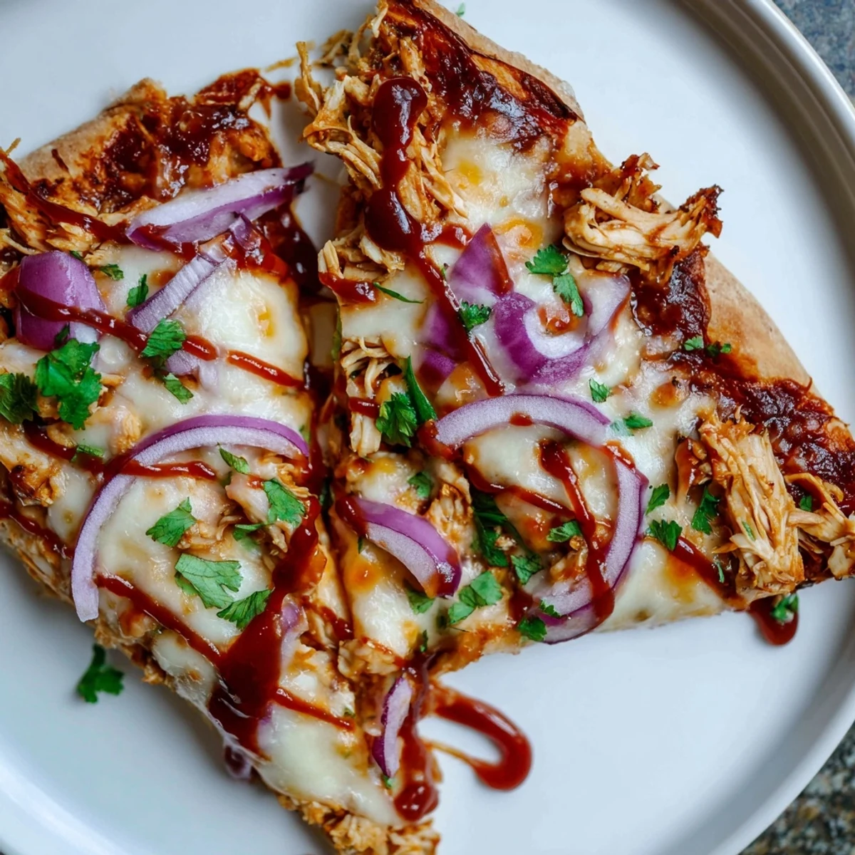 Freshly baked BBQ Chicken Pizza with Red Onion is cut into wedges, revealing a bubbly cheese layer and tender chicken, ready to be served at a casual dinner party.