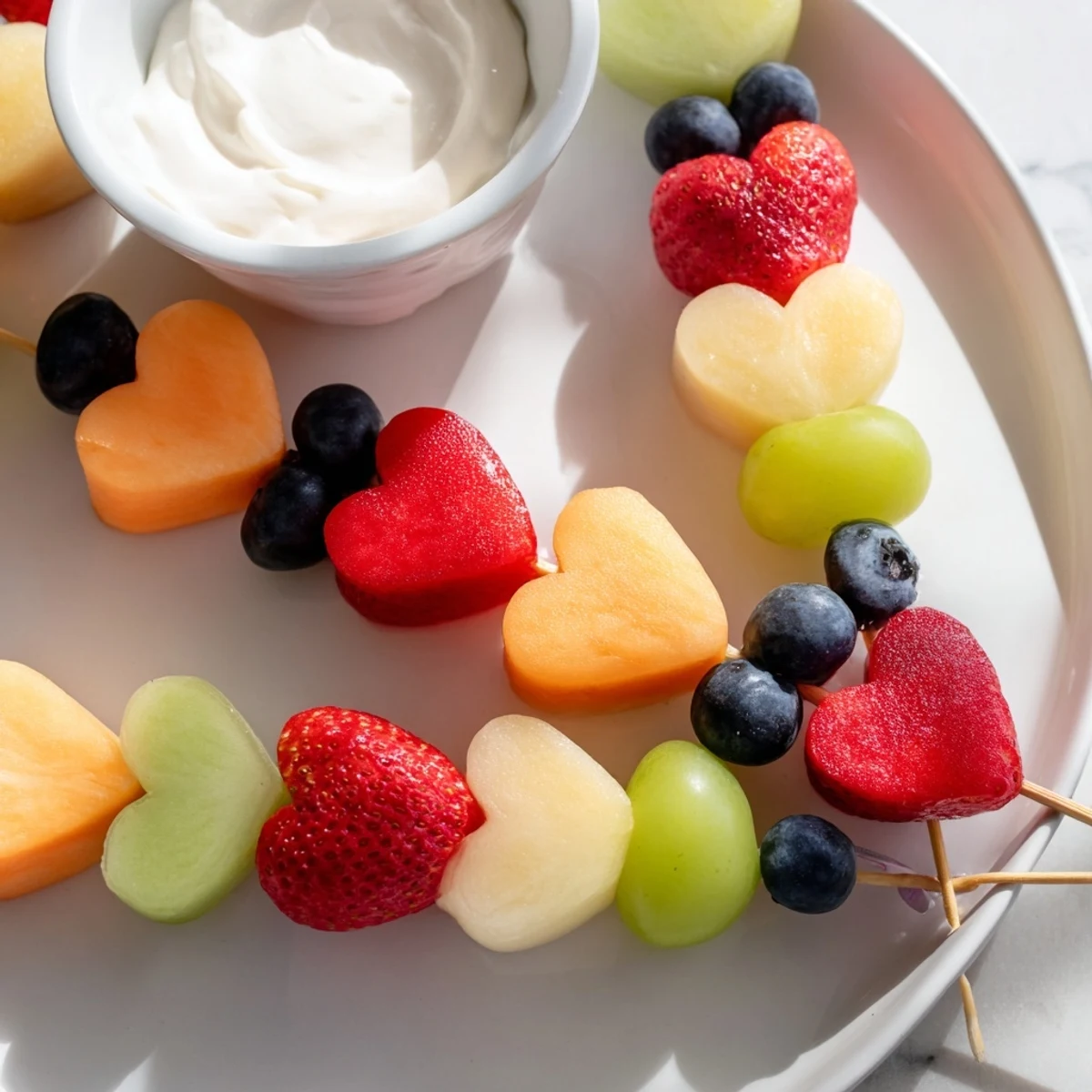 A platter of Sweetheart Fruit Skewers with Yogurt Dip, featuring fresh cantaloupe, strawberries, and a creamy honey dip.