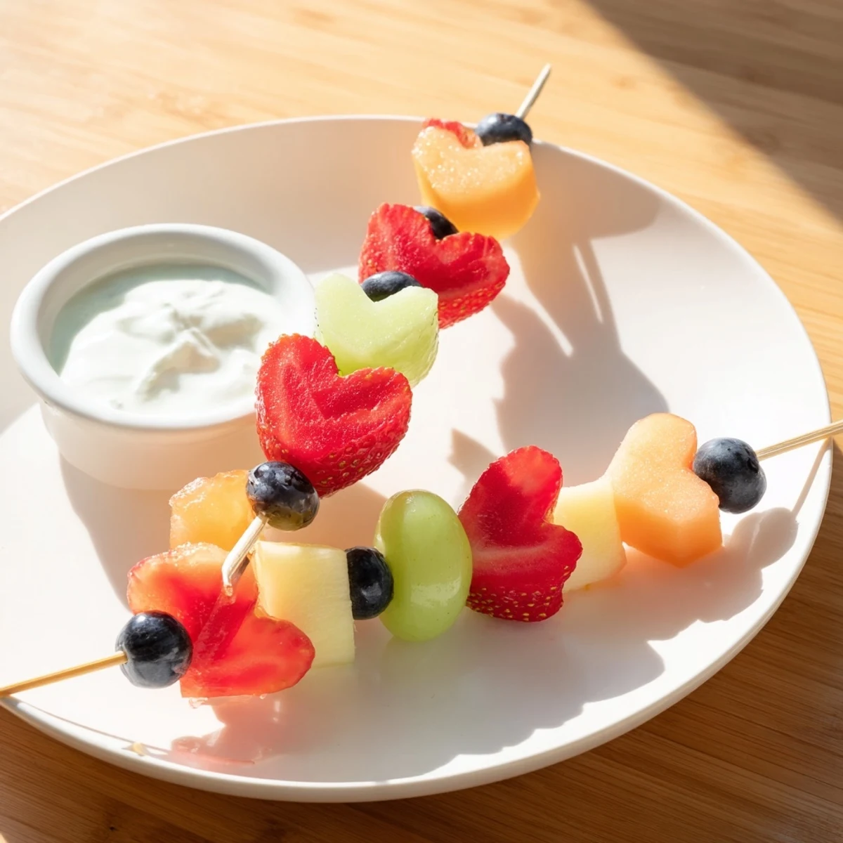 Close-up view of Sweetheart Fruit Skewers with Yogurt Dip showing juicy watermelon hearts and sweet blueberries on skewers.