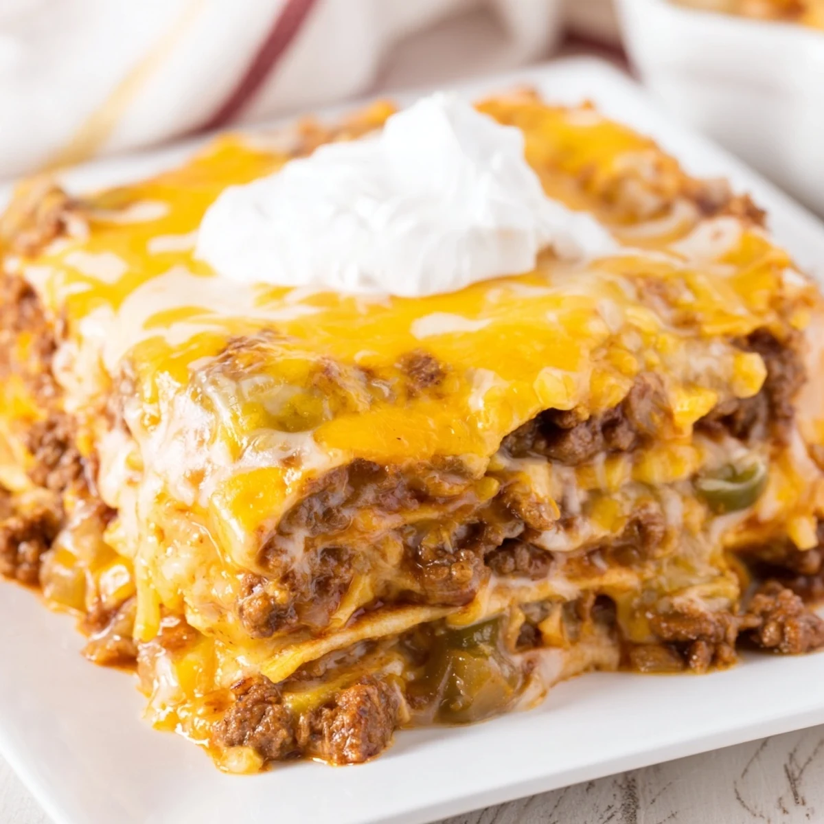 A close-up shows layers of tortillas, seasoned beef, and melted cheddar in the Tex-Mex casserole.