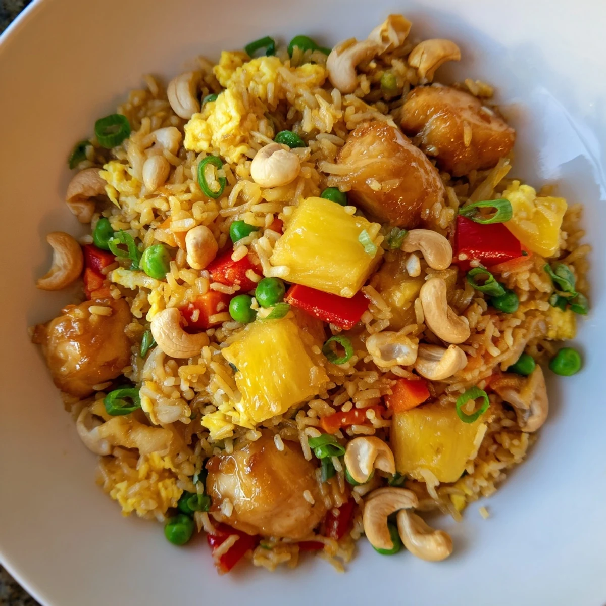 A close-up of Pineapple Chicken Fried Rice with Cashews showing juicy pineapple chunks, tender chicken, and red bell pepper mixed into fluffy jasmine rice.
