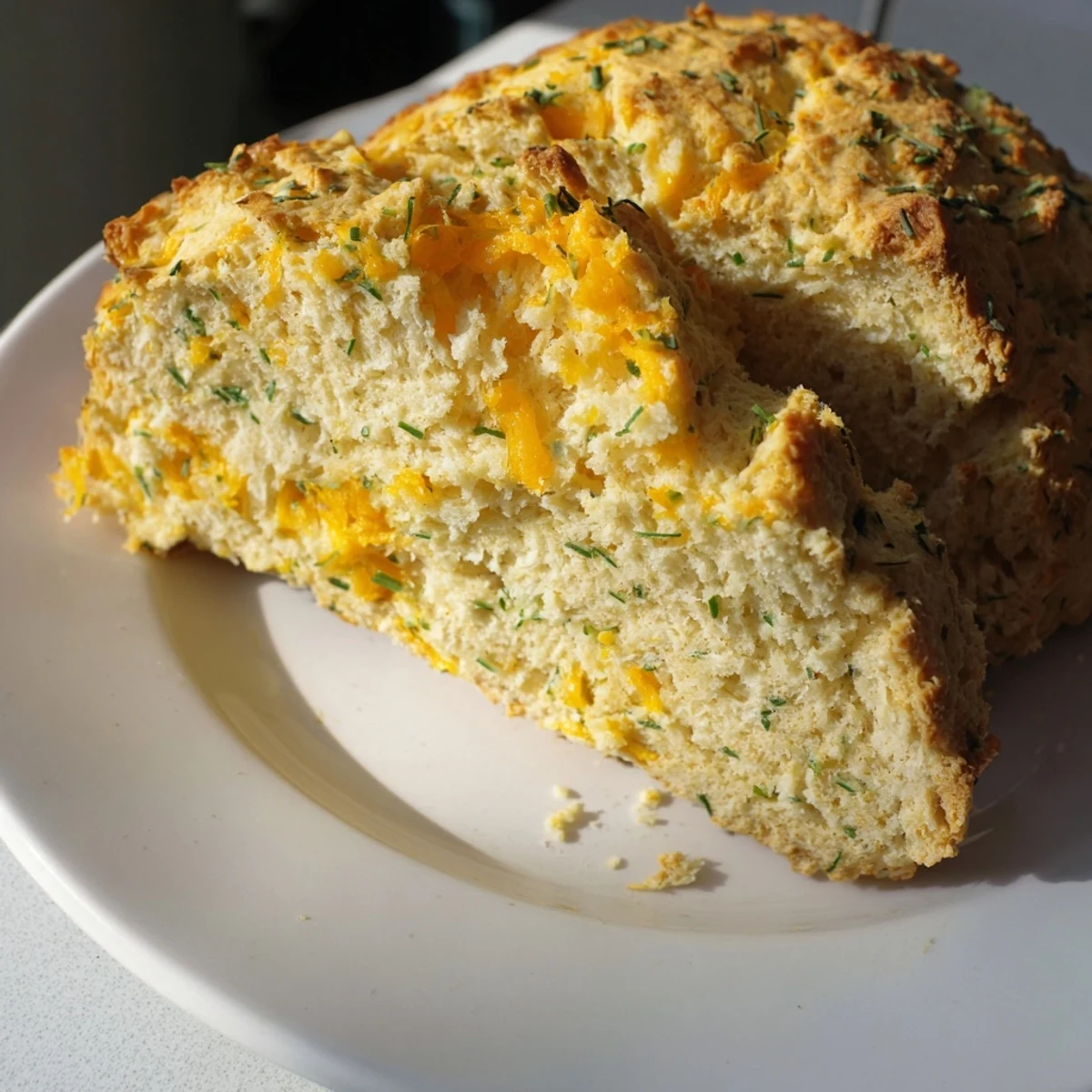 Warm Savory Cheddar & Chive Irish Soda Bread served beside a bowl of soup, perfect for a cozy dinner.