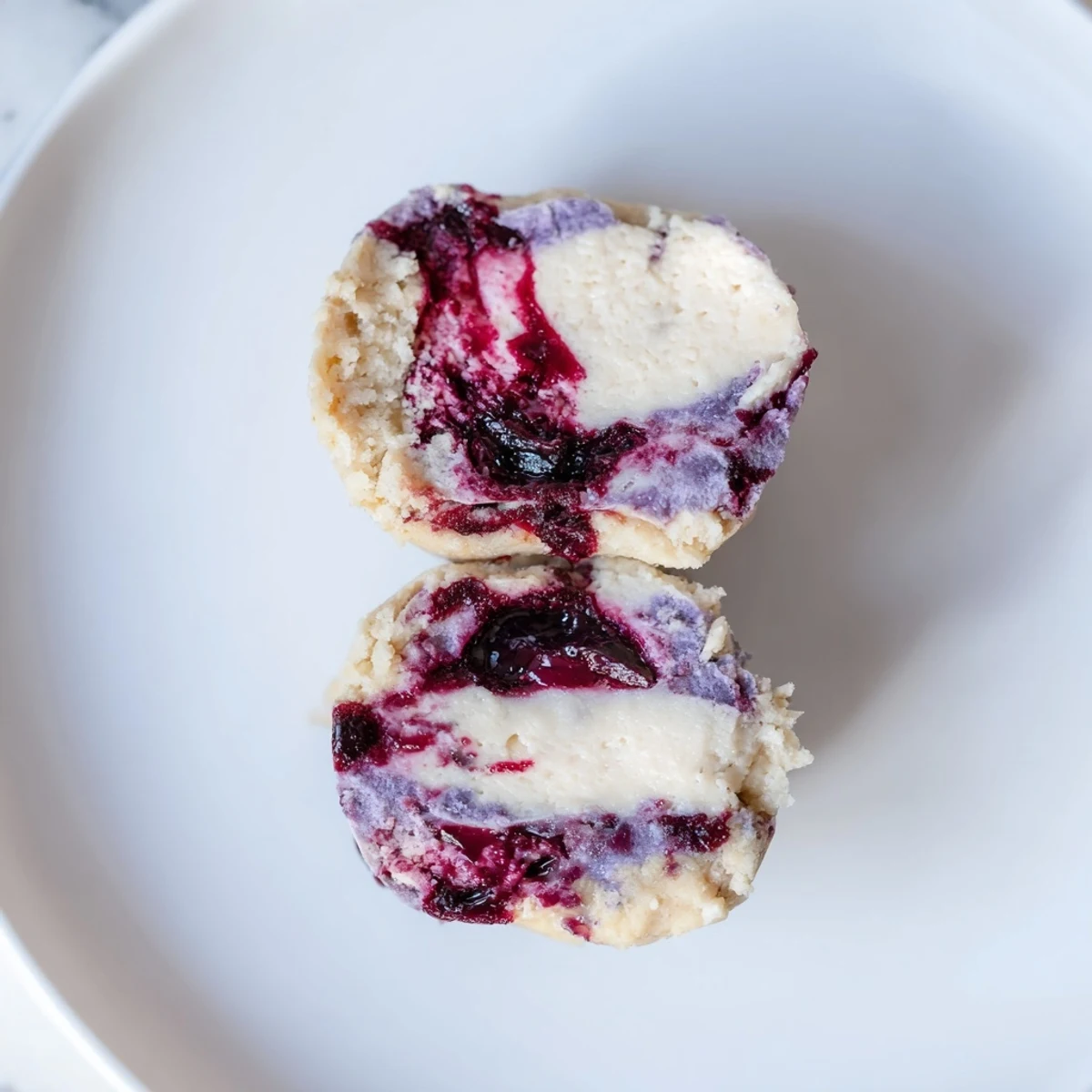 A close-up view of Blueberry Cheesecake Protein Bites reveals a textured almond flour base and rich cheesecake layer.