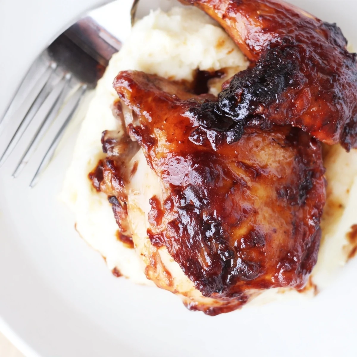 Golden-brown chipotle honey chicken thighs with crispy skin sit beside creamy smoked Gouda mashed potatoes garnished with fresh chives.