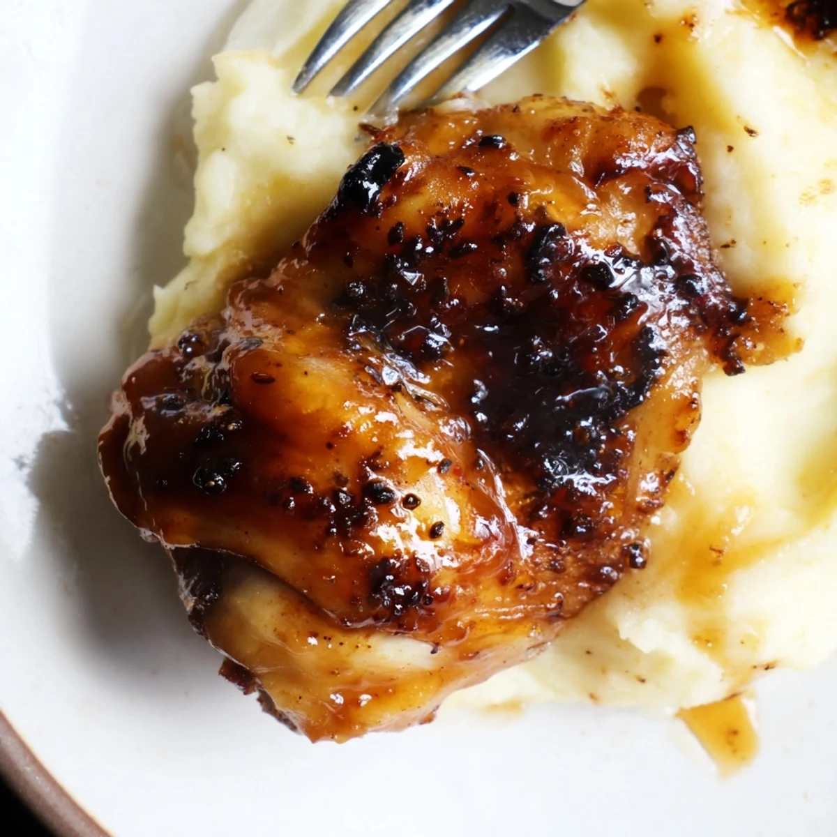 Tender chipotle honey chicken thighs glazed in a spicy-sweet sauce served alongside fluffy, cheesy smoked Gouda mashed potatoes.