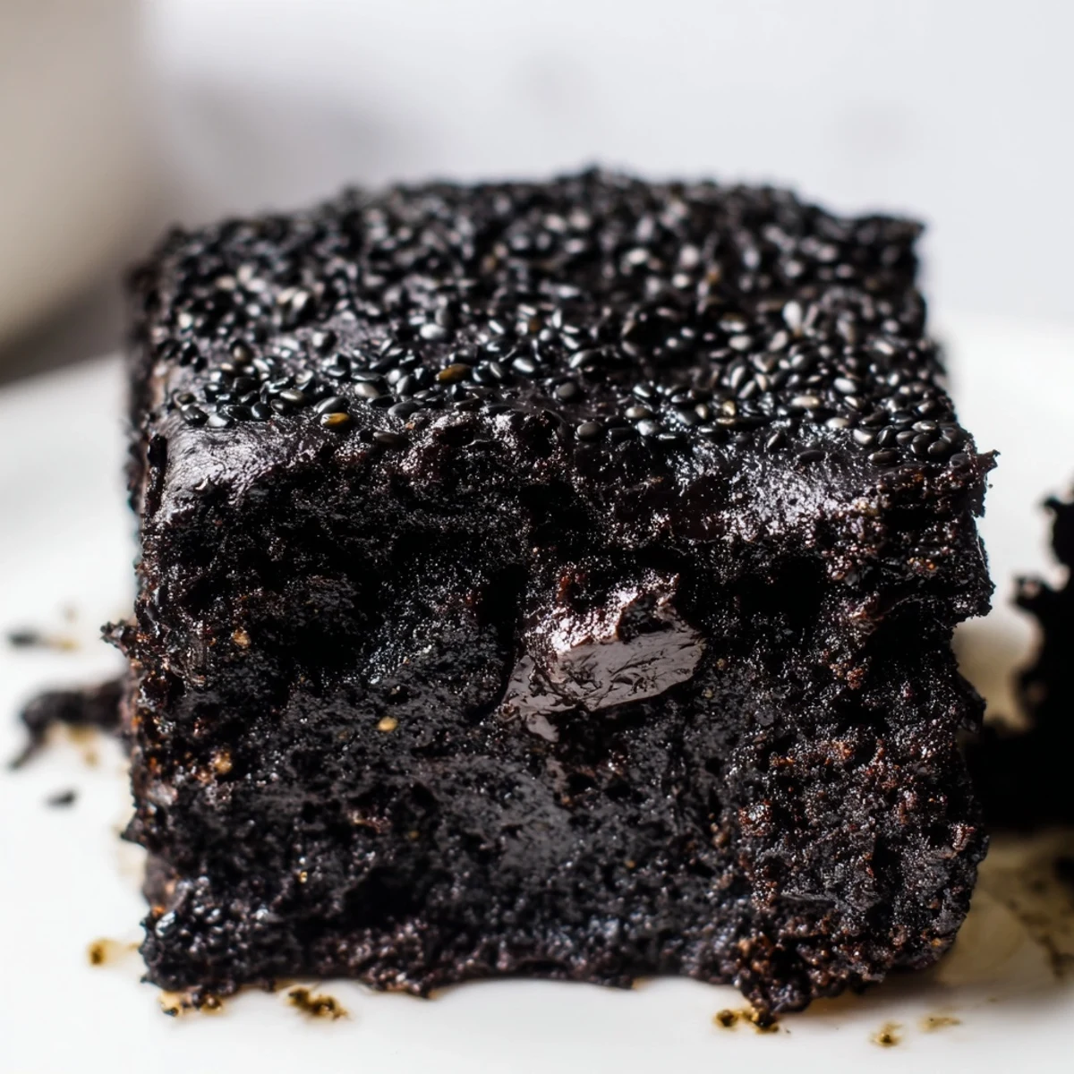 Warm, fudgy Black Sesame Brownies are cut into squares on a wooden board with sesame seeds sprinkled on top.
