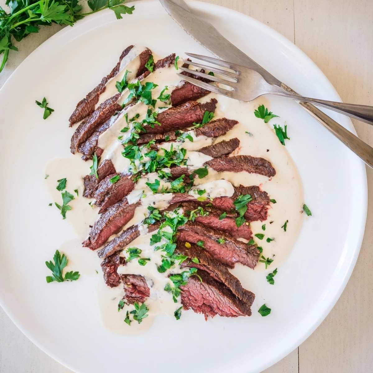 Sizzling sear marks on flank steak topped with creamy roasted garlic sauce, served on a rustic plate for dinner.