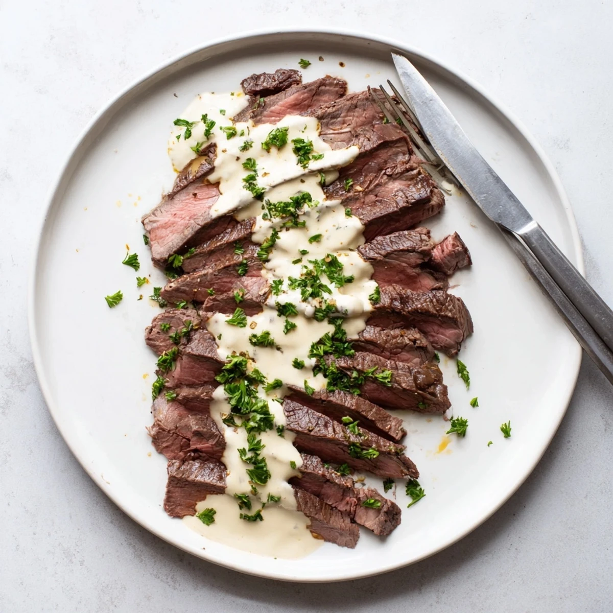 Juicy flank steak with roasted garlic sauce sliced thin, drizzled with velvety sauce and garnished with fresh parsley.