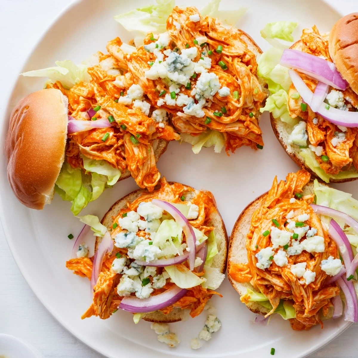 Golden toasted buns hold spicy Buffalo chicken sliders topped with crunchy lettuce and blue cheese crumbles for gatherings.
