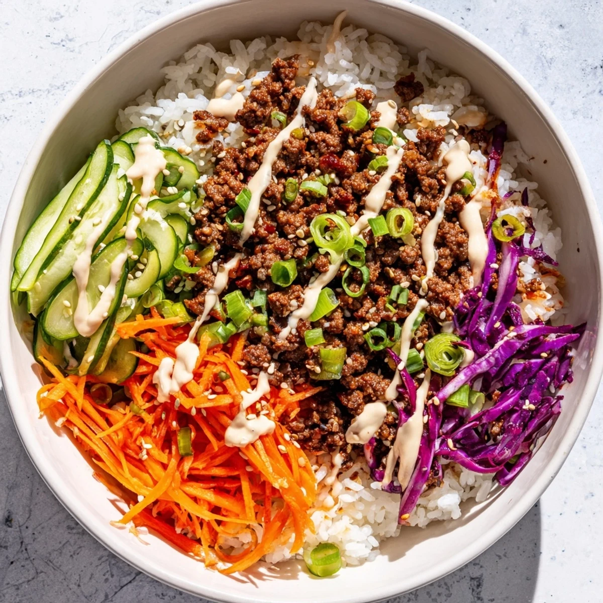 Korean Beef Bowl with Spicy Mayo served in a white bowl with sesame seeds and green onions on top.