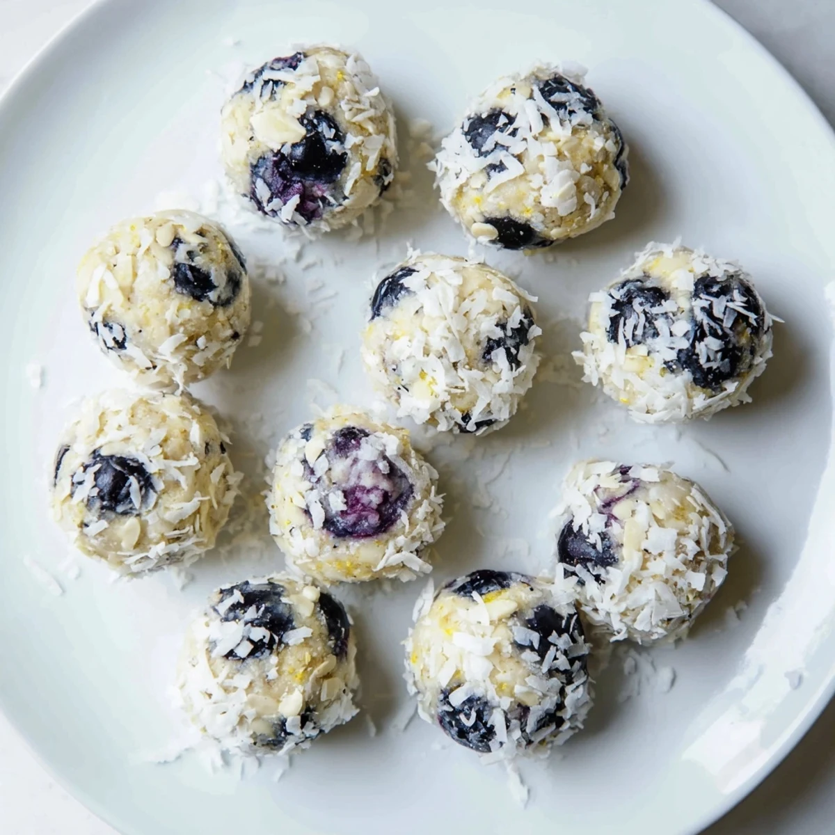 A close-up of Lemon Blueberry Cottage Cheese Protein Bites showing coconut coating and zest.