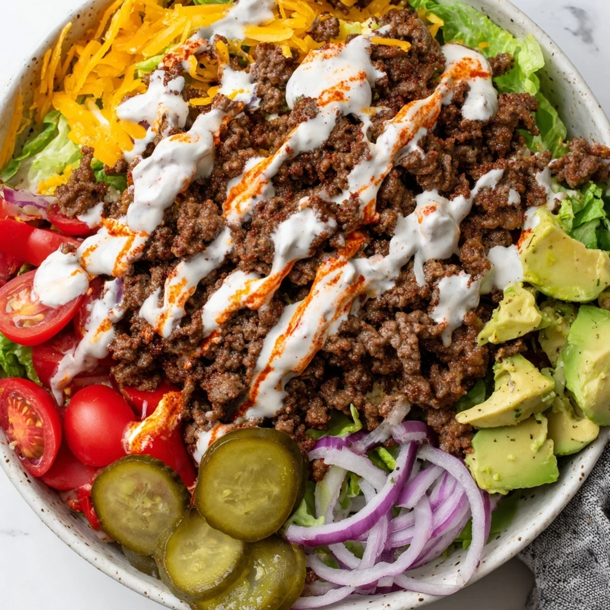 Golden brown seasoned ground beef layered over crisp romaine lettuce in a colorful burger bowl
