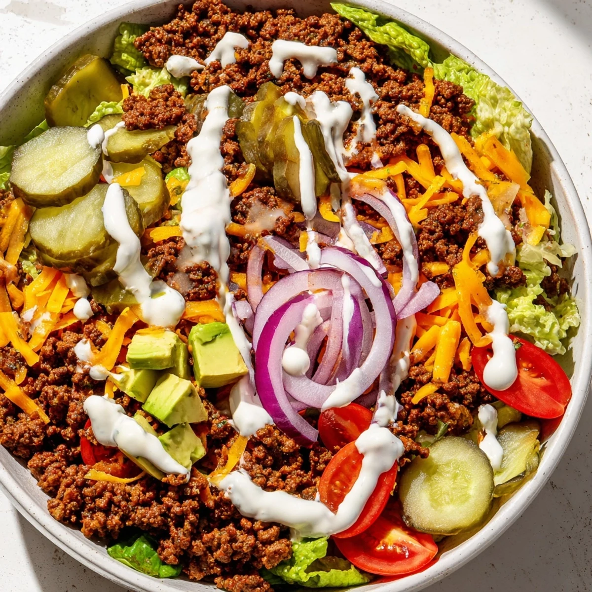 Meal prep burger bowl featuring juicy beef, avocado, pickles, and tangy homemade dressing