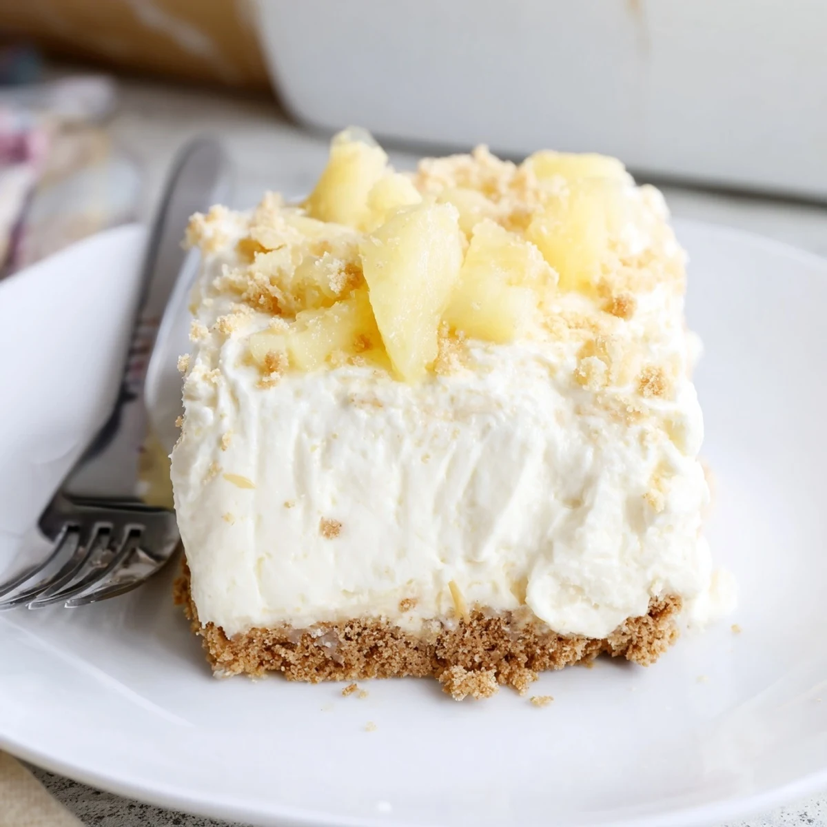 Creamy no bake pineapple cheesecake slice topped with juicy crushed pineapple and fresh mint