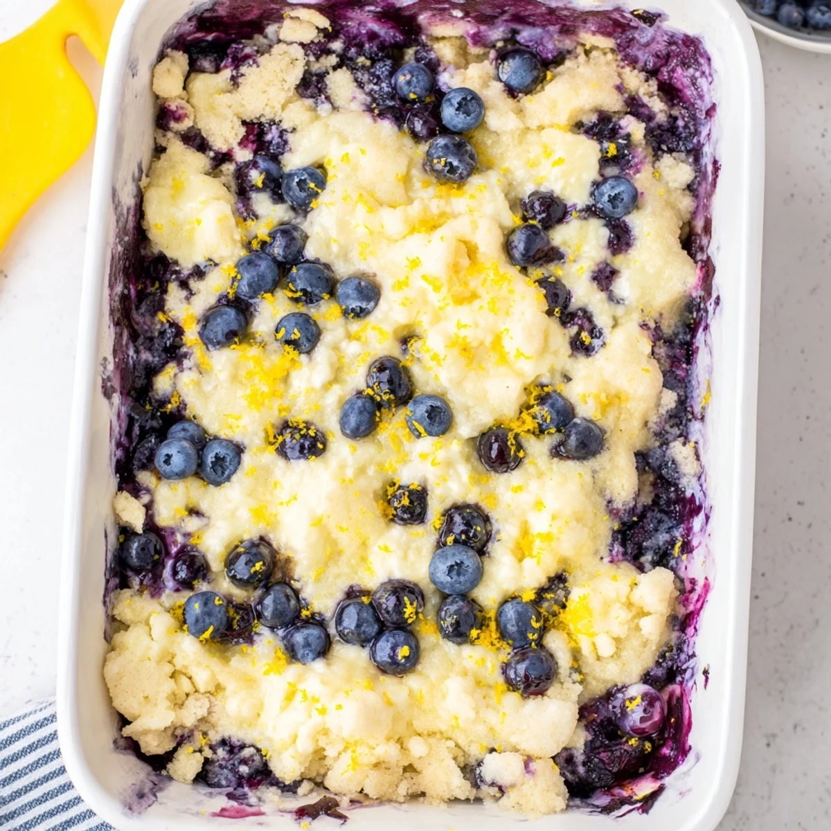 Baked lemon blueberry cheesecake dump cake served warm showing layers of tangy blueberries and velvety cheesecake under crisp cake mix
