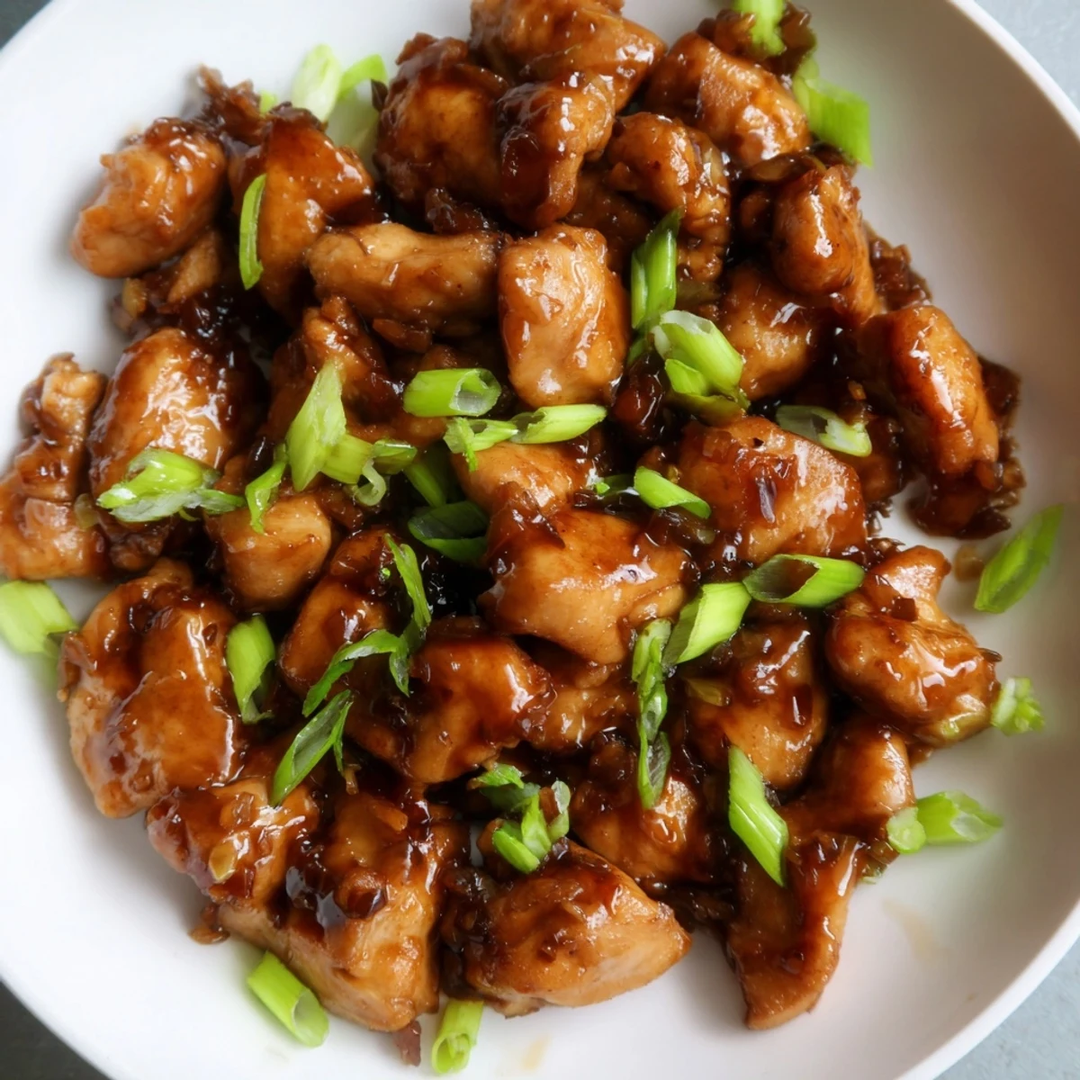 Tender Mongolian chicken simmered in rich brown sugar glaze served over steaming white rice in a bowl