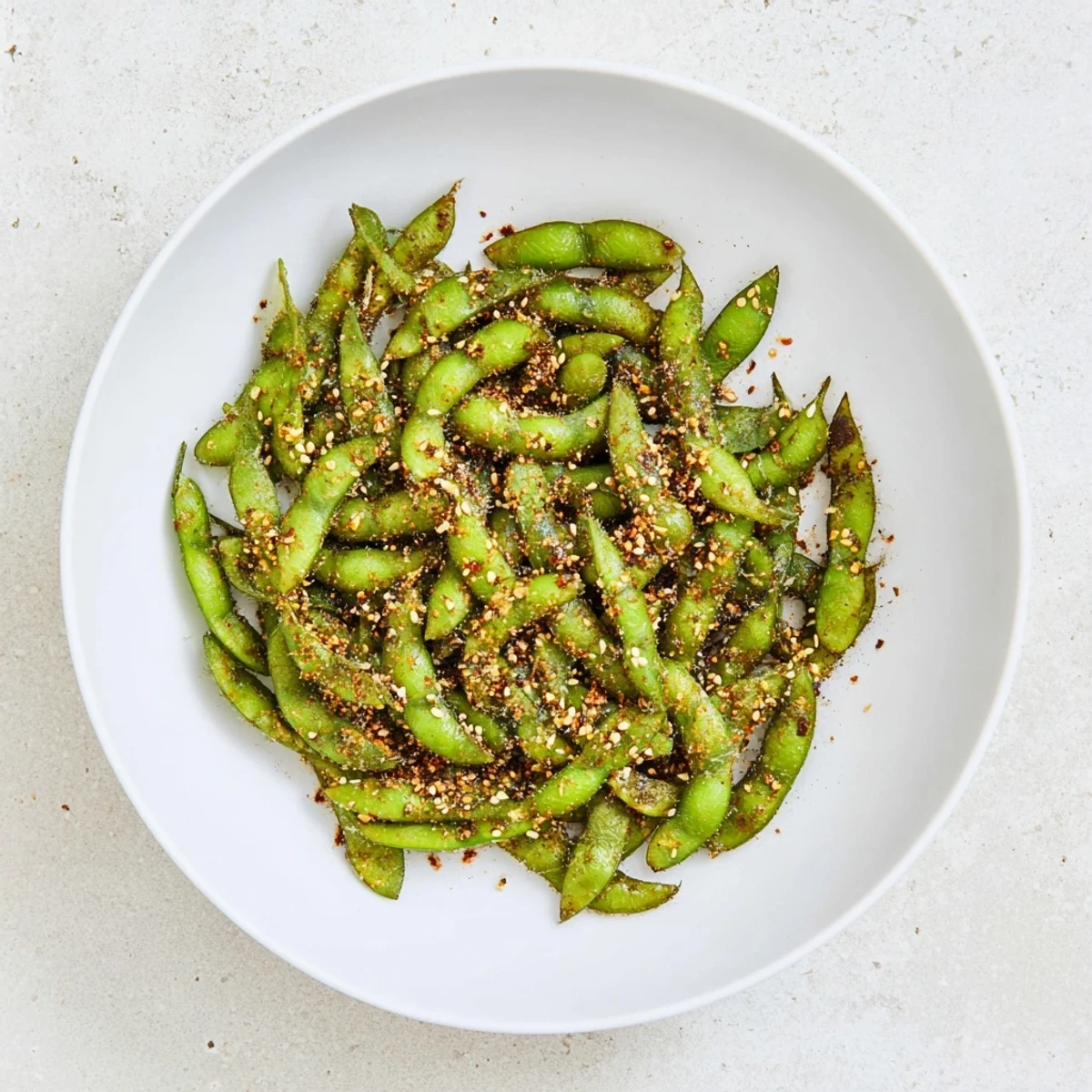 Golden air fryer edamame pods sprinkled with sesame seeds in a rustic serving bowl