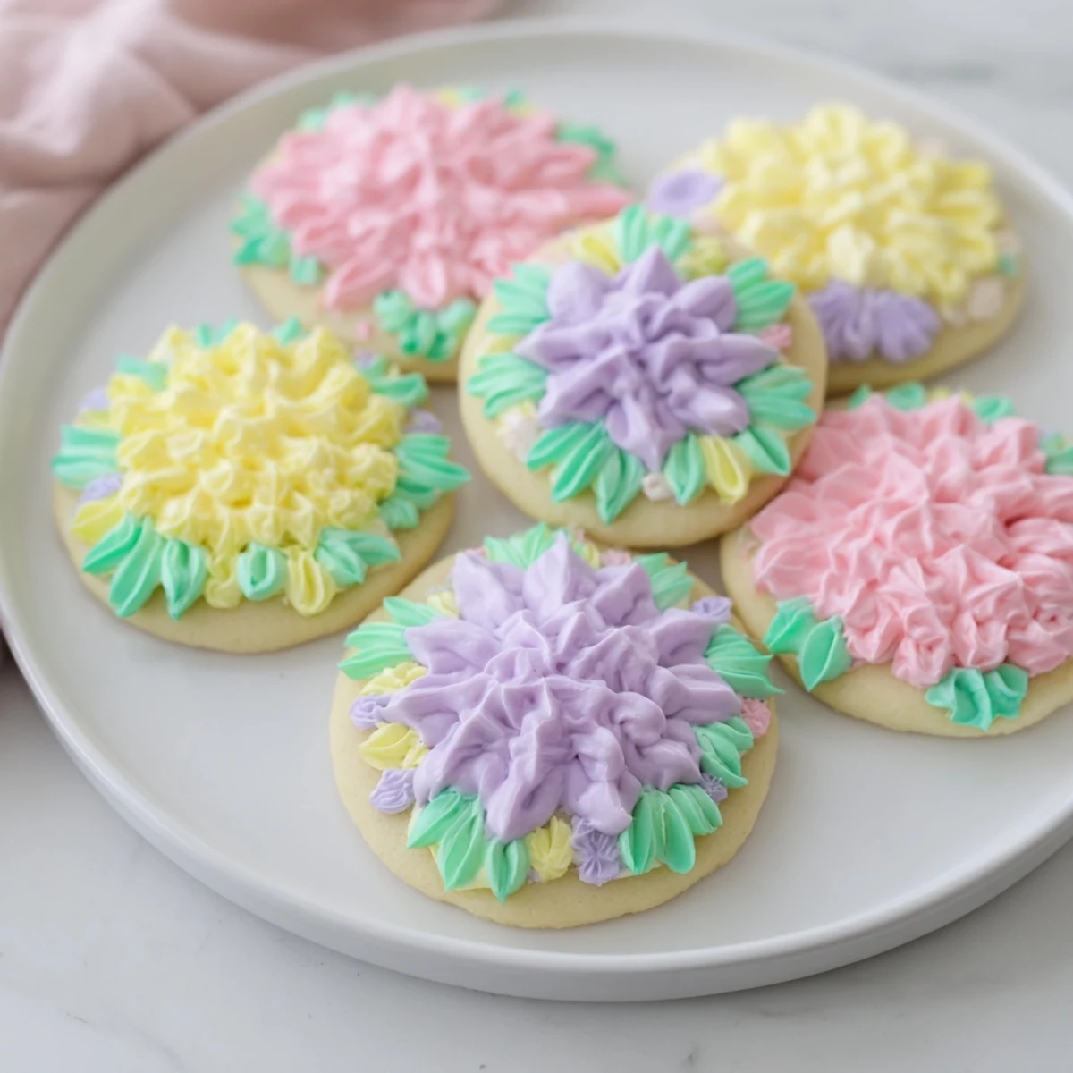 Buttercream flower cookies featuring delicate sugar bases topped with colorful piped buttercream blooms and green leaves