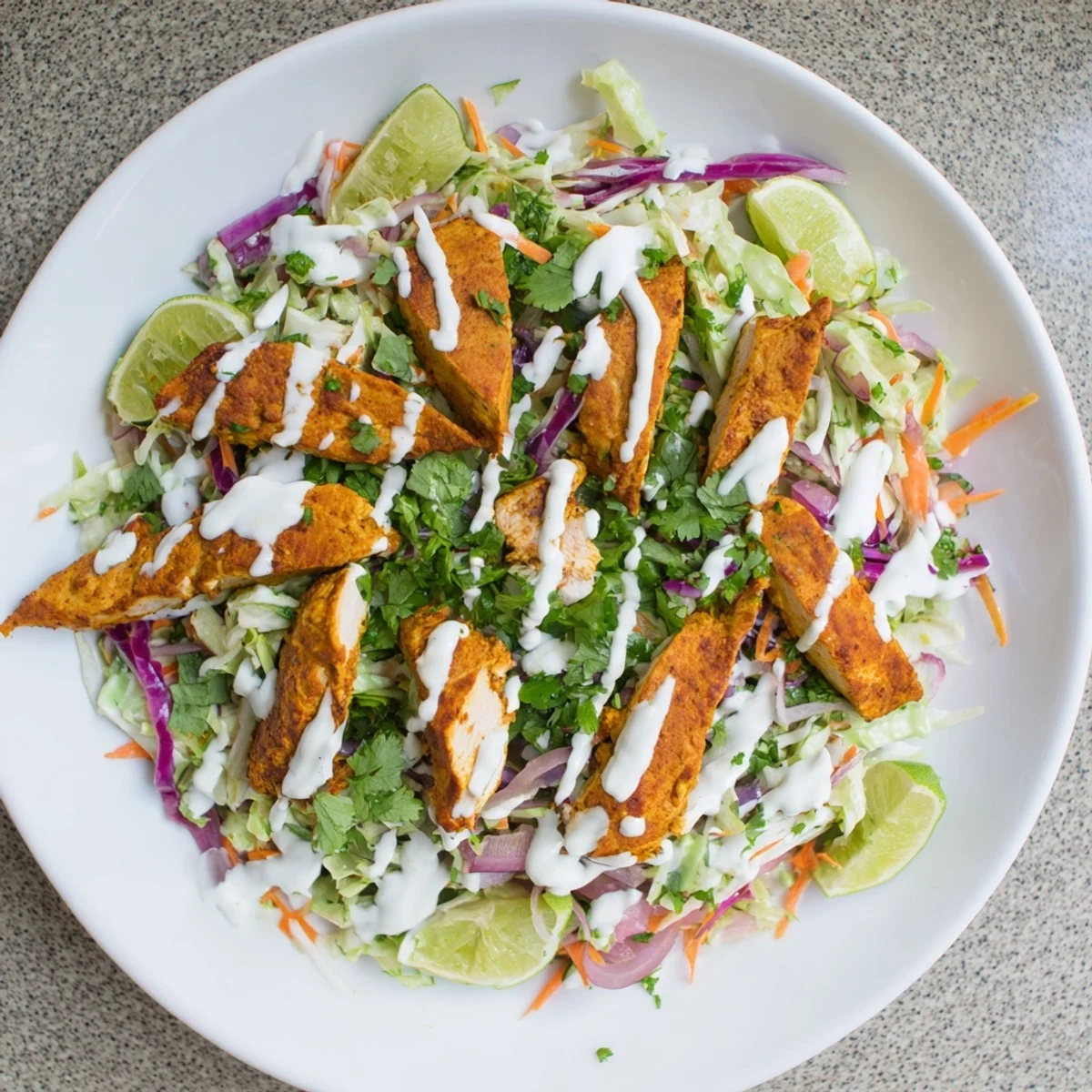 Golden curried chicken breasts sliced over vibrant purple and green lime coleslaw with creamy mint yogurt drizzle