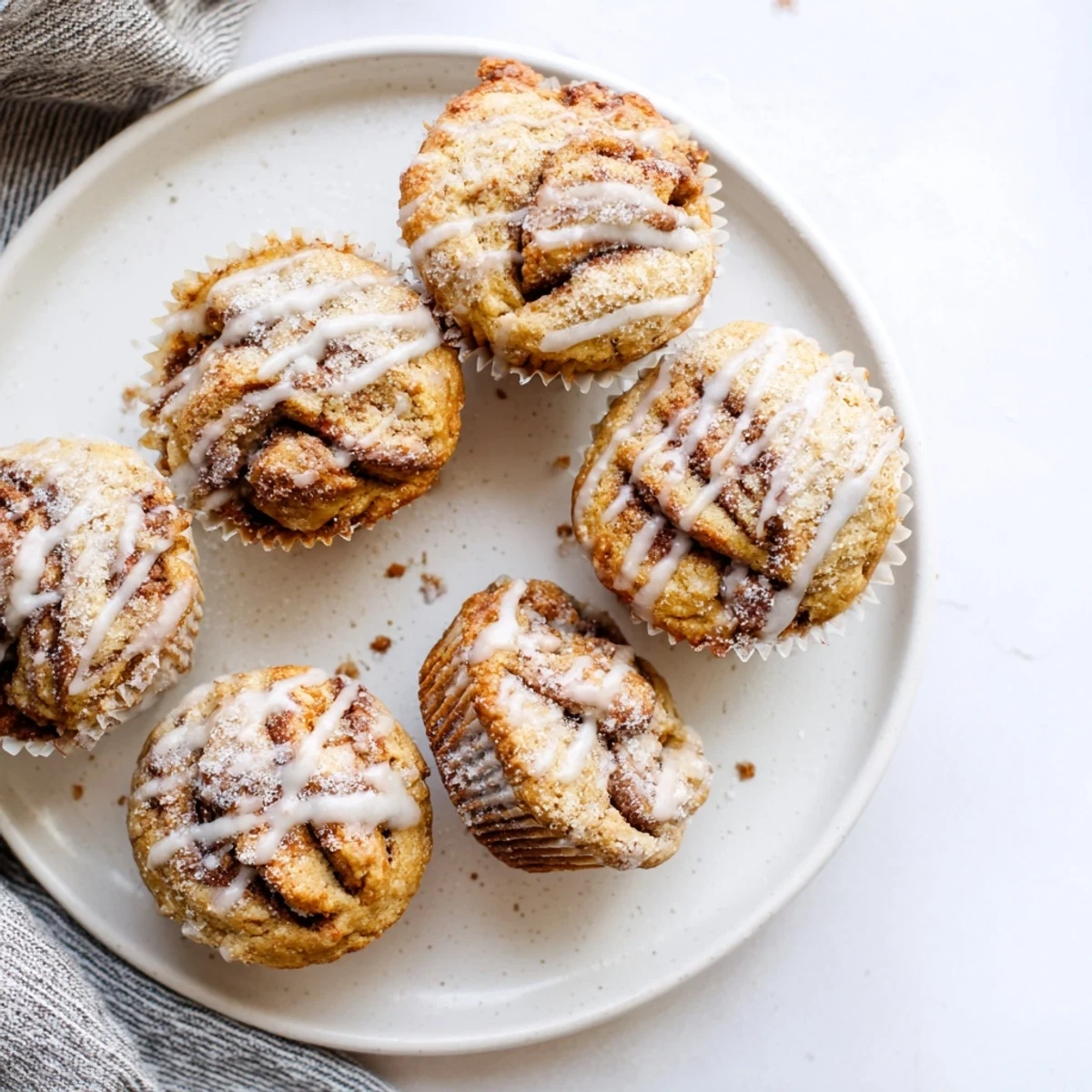 Freshly baked cinnamon roll protein muffins with gooey swirl centers and powdered sugar topping