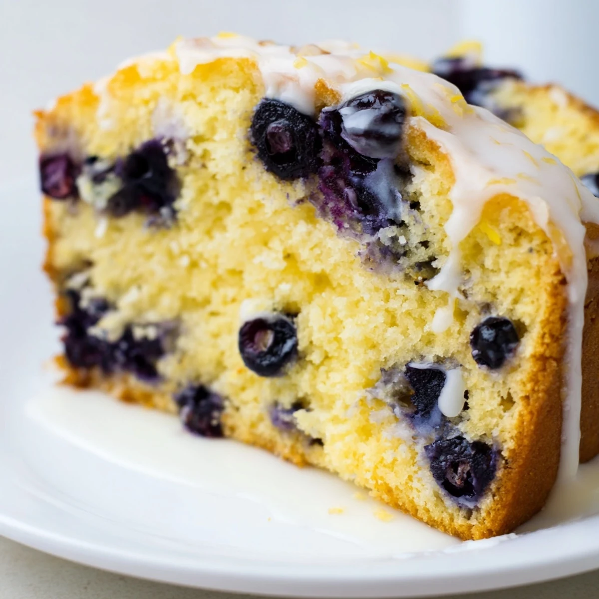 Spring dessert featuring tender lemon blueberry cake with powdered sugar glaze and blueberry garnish