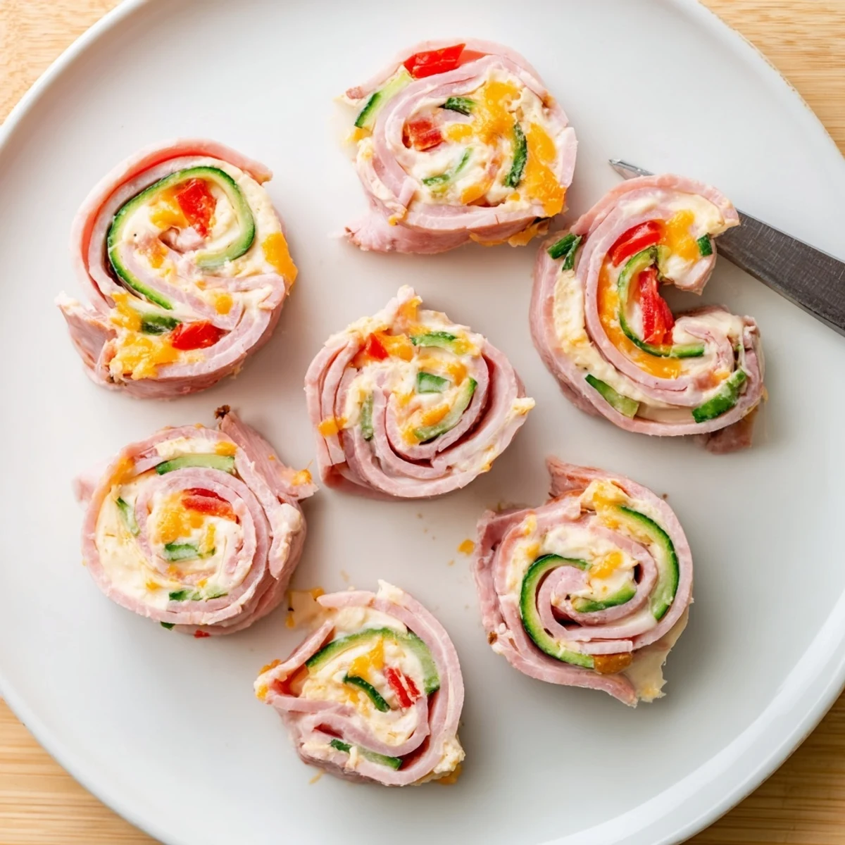 Fresh low-carb keto ham roll ups arranged on a platter with colorful bell pepper strips