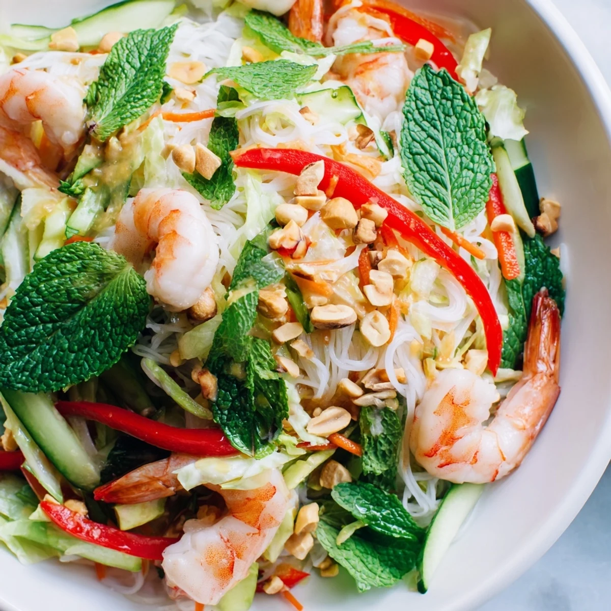 Vibrant salad plate with spring roll ingredients, vermicelli noodles, peanuts, and tangy spicy ginger dressing