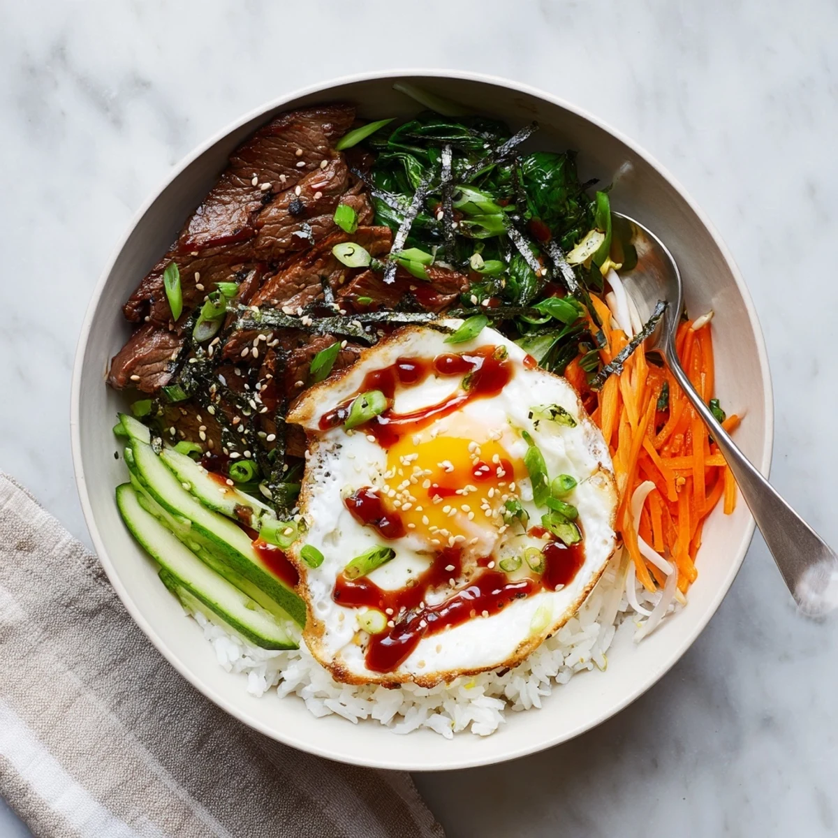 Savory Korean-inspired breakfast bowl with marinated beef, fried egg, and colorful vegetables over fluffy rice