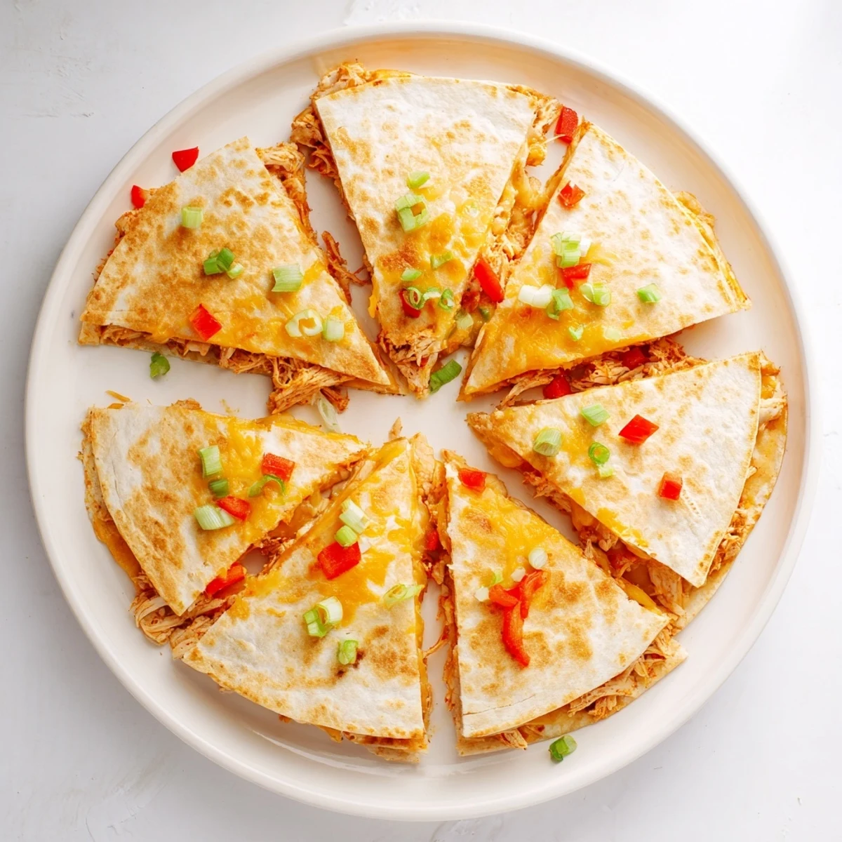 Golden baked chicken and cheese quesadillas with red peppers and green onions on a wooden board