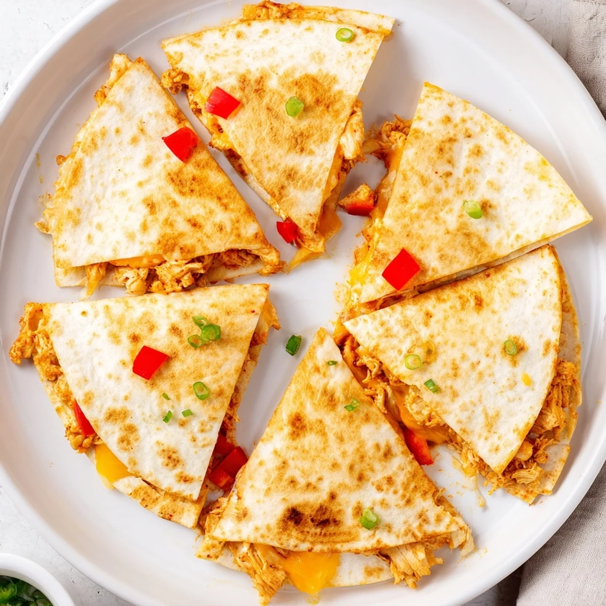 Close-up of easy chicken quesadillas with bubbly cheese topping, served with salsa and sour cream