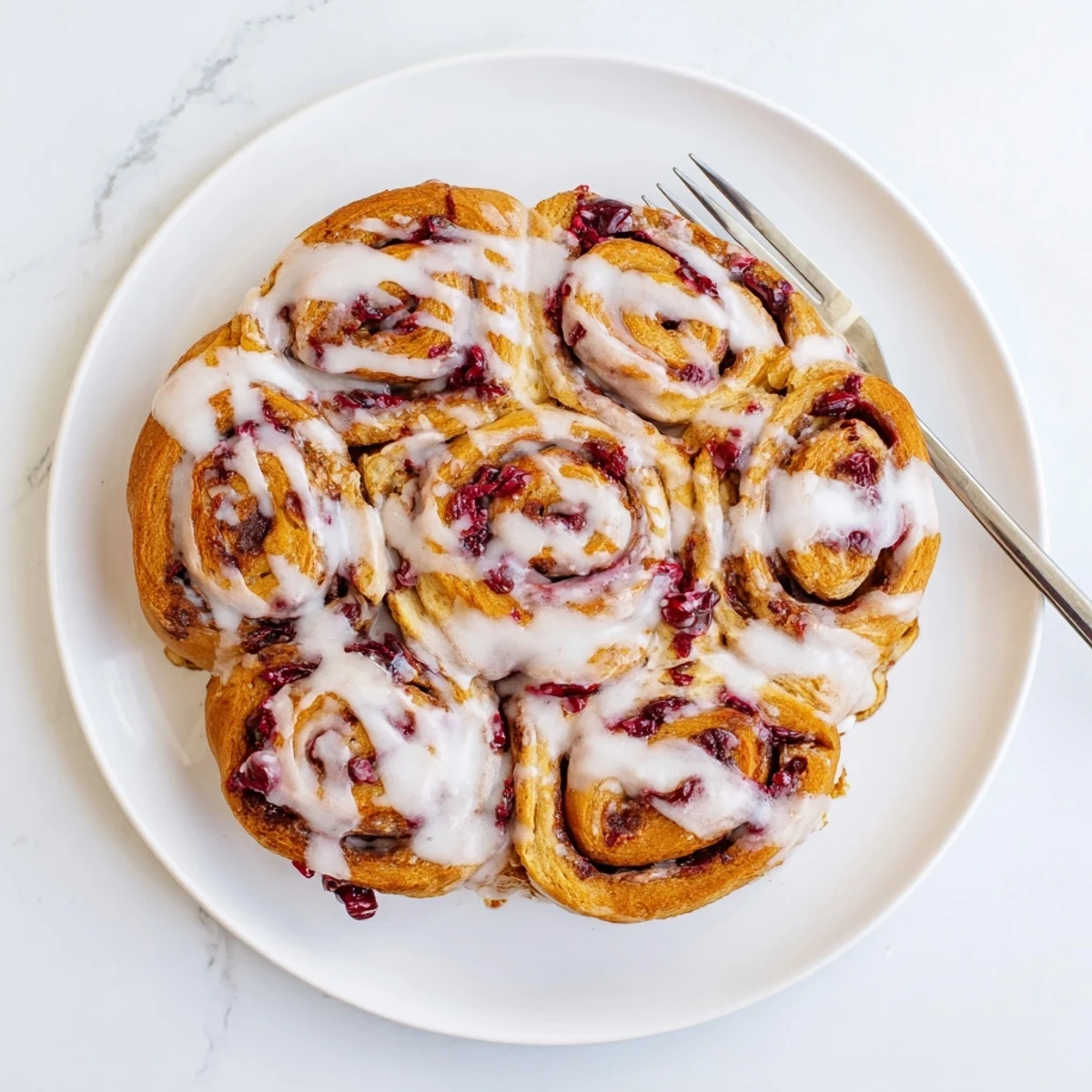 Warm homemade cherry cinnamon rolls topped with creamy glaze and juicy cherry filling layers