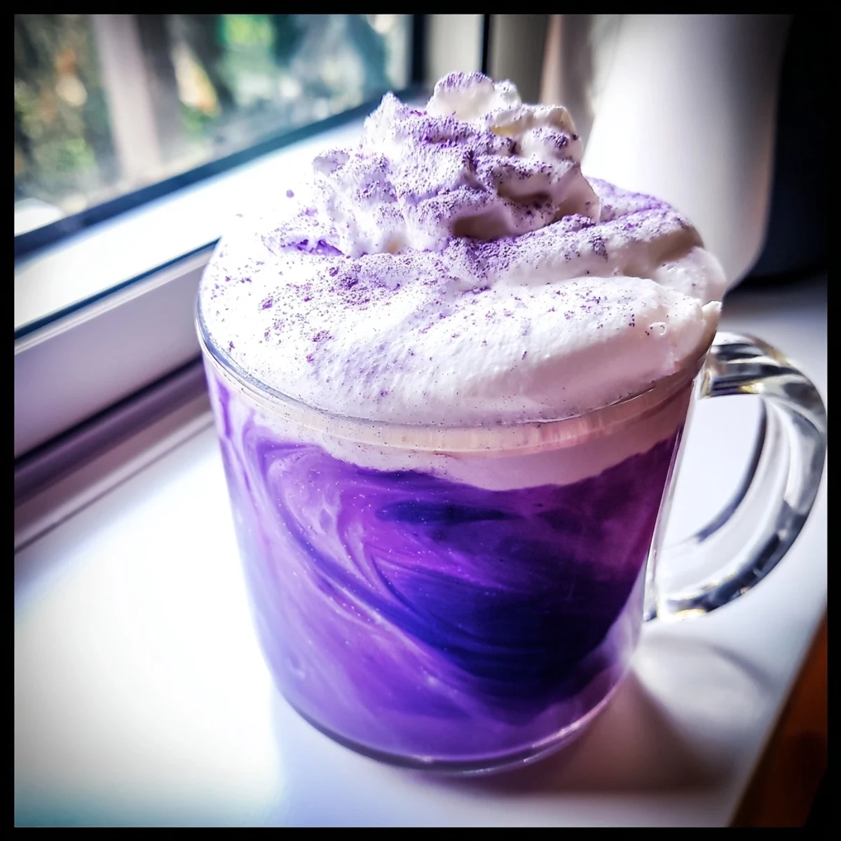 Hot ube latte in white mug with rich purple color and dusting of ube powder on top