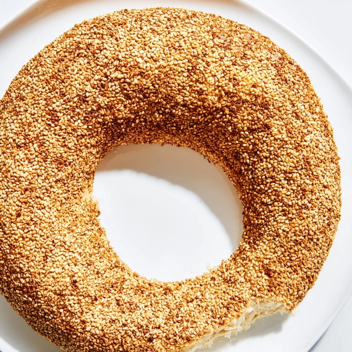 Homemade sesame bread rings arranged on parchment paper, showcasing golden exteriors and generous seed coating