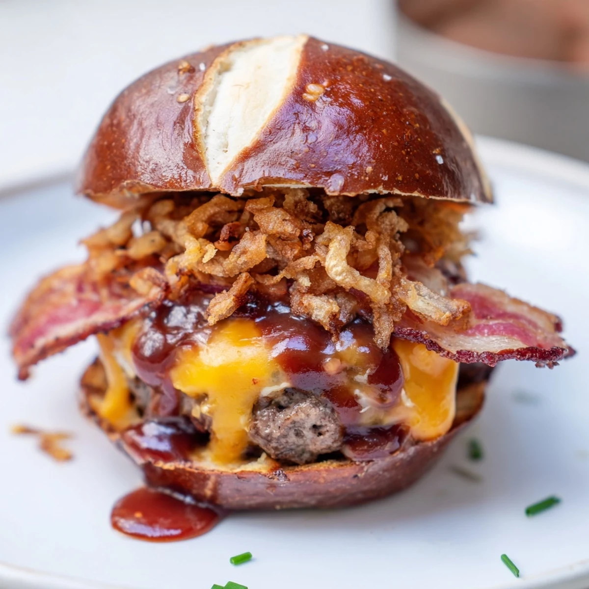 Mouthwatering Pretzel Cowboy Sliders assembled on toasted pretzel buns with cheese, barbecue drizzle, and fresh chive garnish