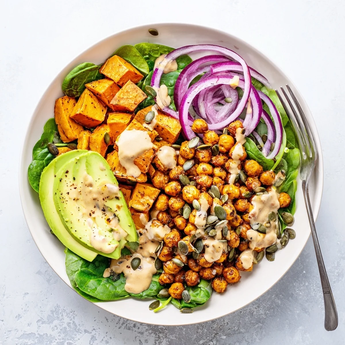 Golden roasted sweet potato and chickpea bowls drizzled with creamy tahini dressing over fresh greens