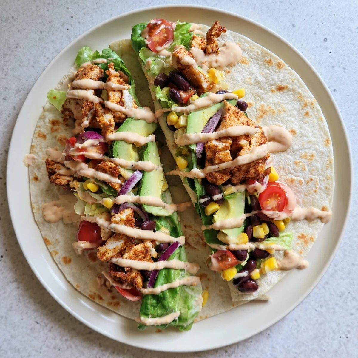Handheld flour tortilla filled with spicy cooked chicken black beans corn and zesty dressing