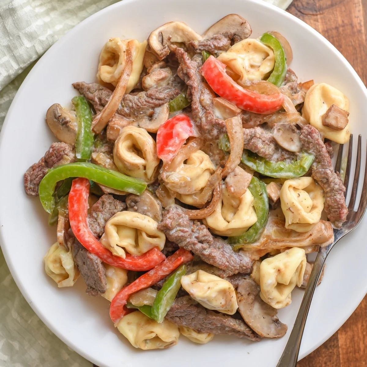 Creamy Crock Pot cheesesteak tortellini with tender beef slices, peppers, and melted provolone cheese