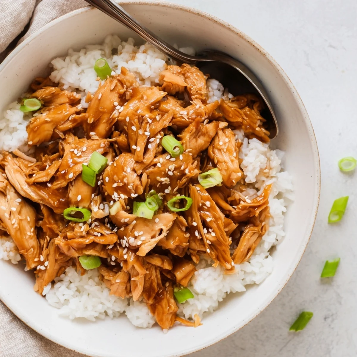 Slow cooker Teriyaki Chicken with shredded meat coated in glossy brown honey-garlic glaze and sesame seeds