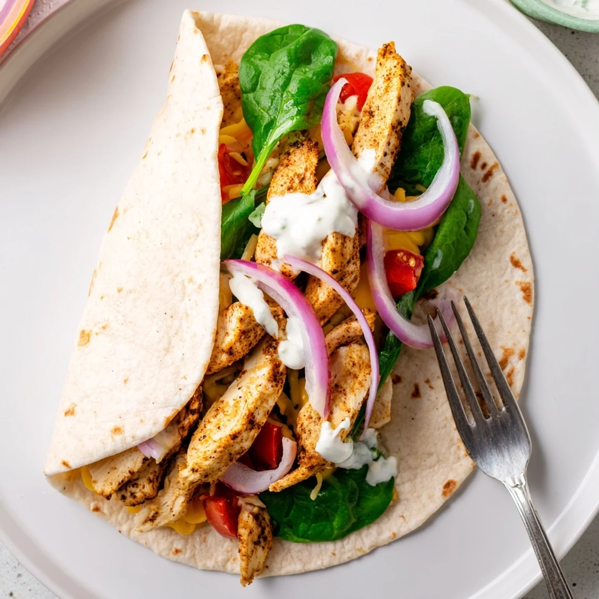 Delicious low carb cheesy garlic chicken wraps served on a white plate with fresh filling visible