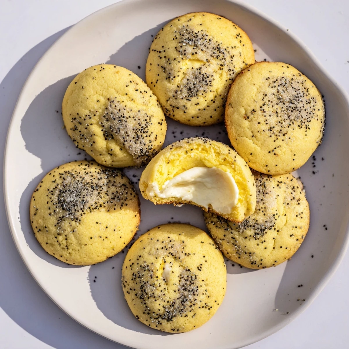 Soft baked lemon poppy seed cheesecake cookies with white filling and poppy seed topping