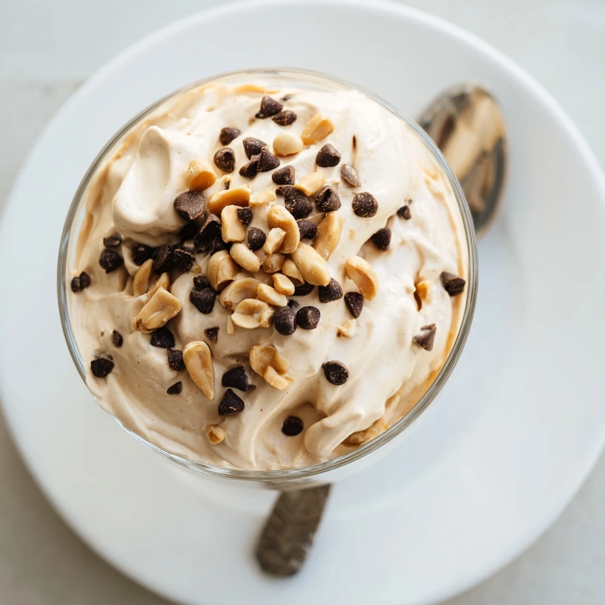 Creamy peanut butter and Cool Whip mousse topped with chocolate chips and crushed peanuts in clear glass